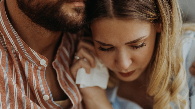 man embracing woman holding tissue