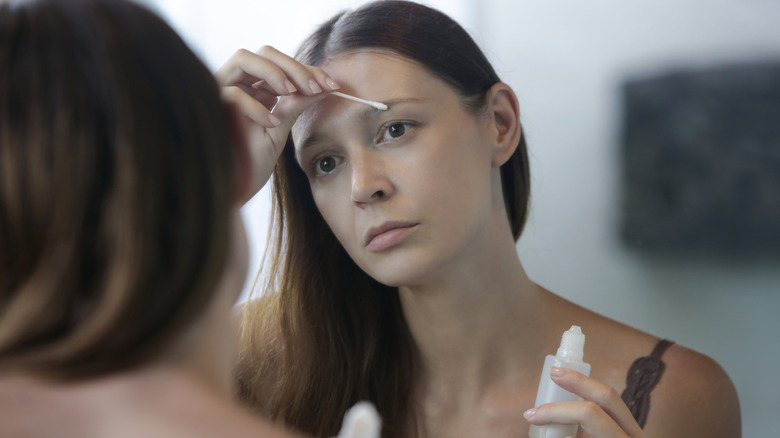 Woman applying serum to eyebrows