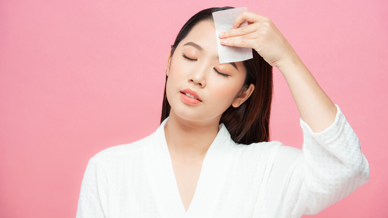 Woman blotting her oily face