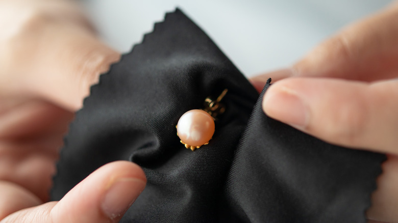 hands polishing pink pearl earring