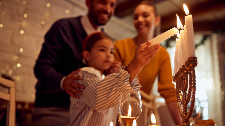 Parents with daughter lighting Menorah