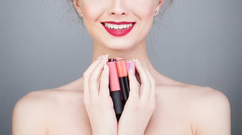 woman holding piles of lipglosses in her hand