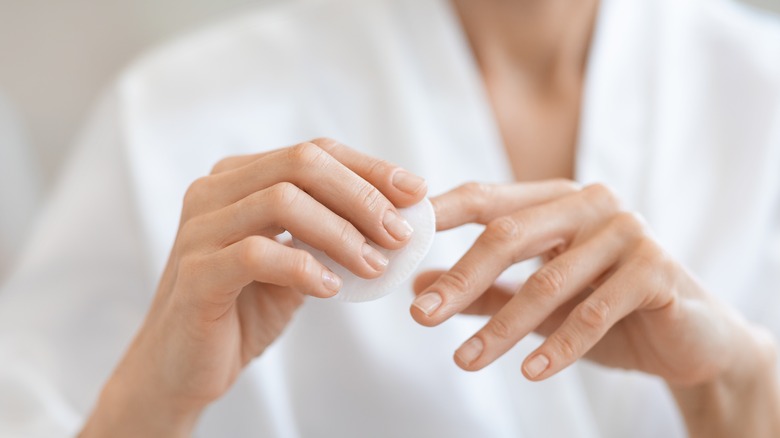 Woman rubbing cotton pad on nails