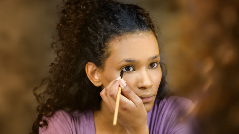 Woman applying eyeliner to lower lash line