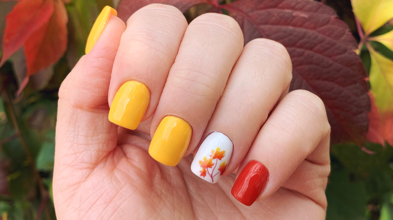 Fall-themed squoval manicure with leaves in background