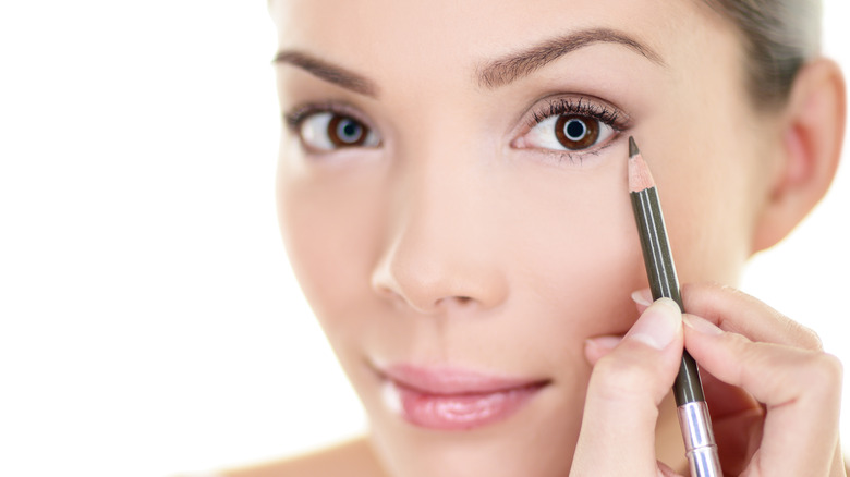 A woman applying eyeliner 