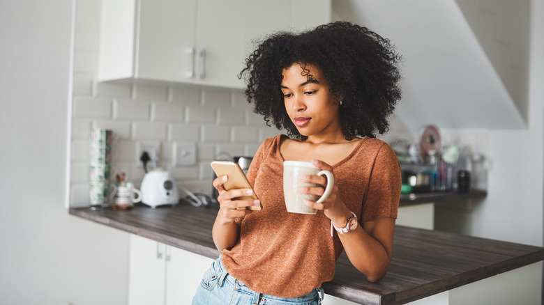 woman with mug using phone