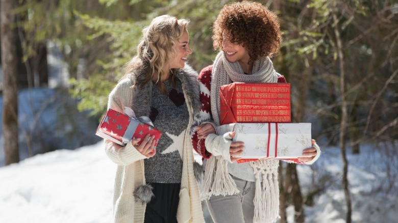 Two women carrying Christmas presents