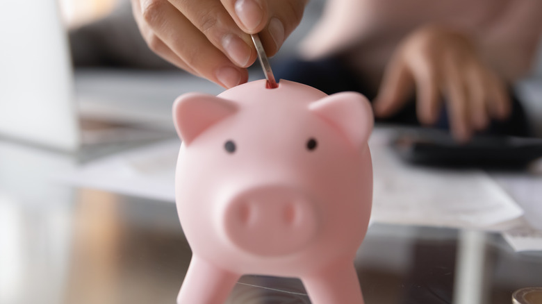 woman putting coin in piggy bank