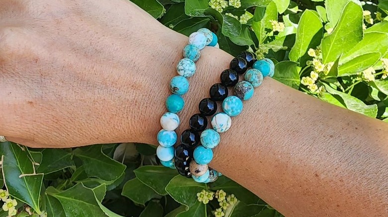 Wrist displaying blue, black beaded bracelets