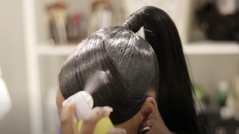 A woman using spray on her ponytail