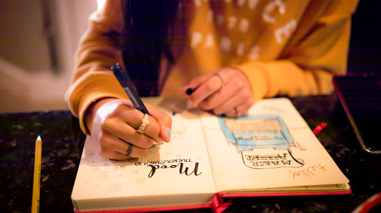 person writing in creative journal