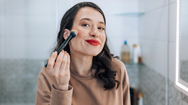smiling woman using makeup brush