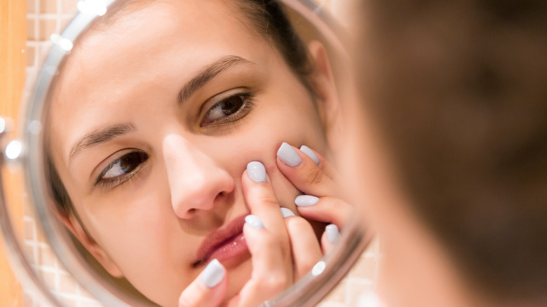 Woman squeezing pimple on face