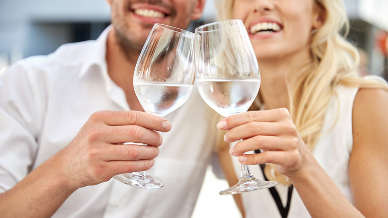 couple toasting wine glasses of water