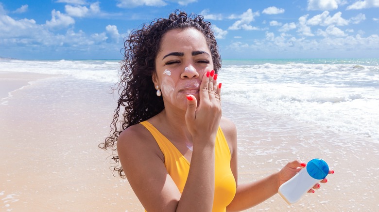 A woman applying sunscreen on her face