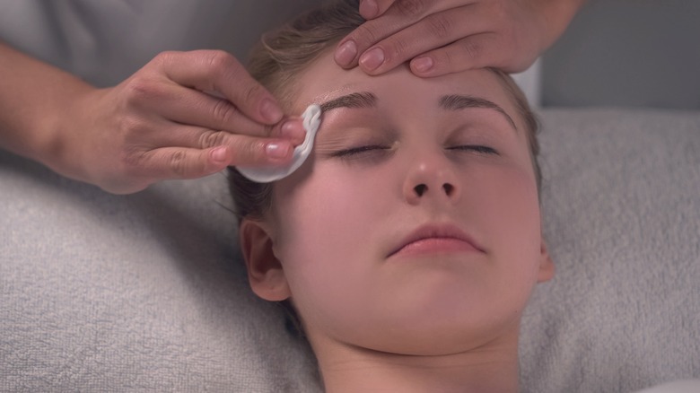 esthetician disinfecting waxed eyebrows