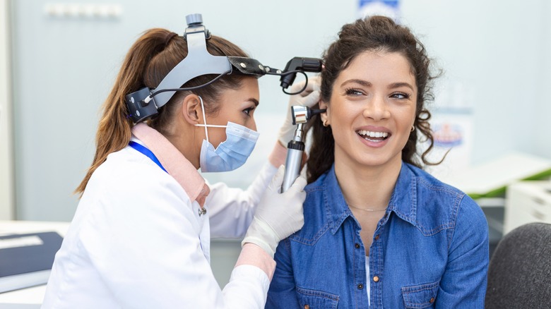 Doctor looking at woman's ear