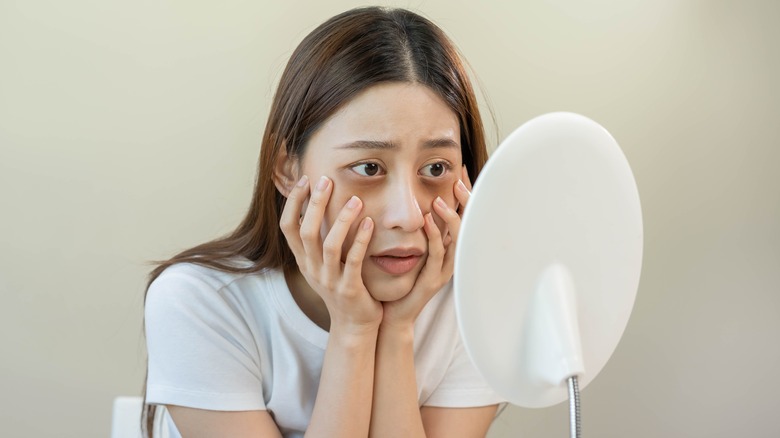 Woman looking at eyes in mirror