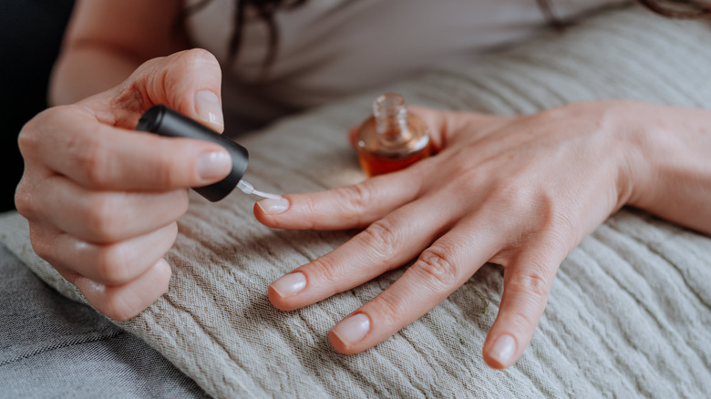 person applying base coat to nails