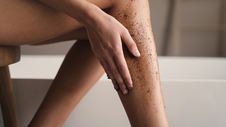 woman exfoliating legs with scrub