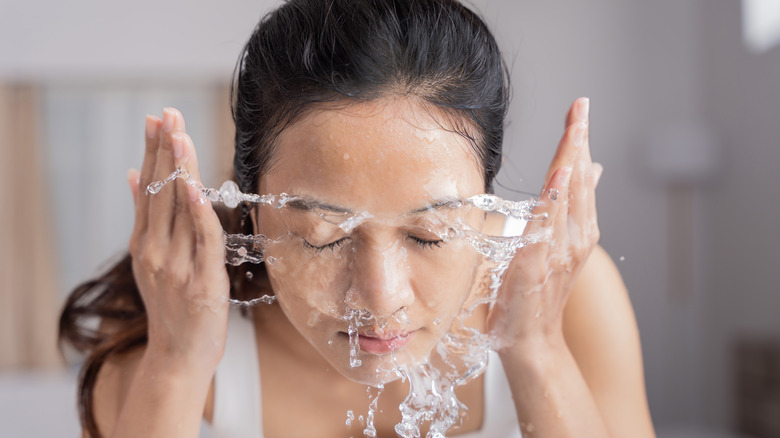 asian woman washing her face with water