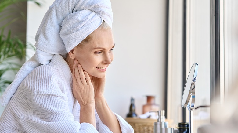 woman looking at face in towel 