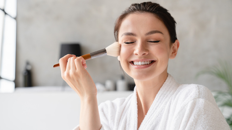 woman applying make up to her face