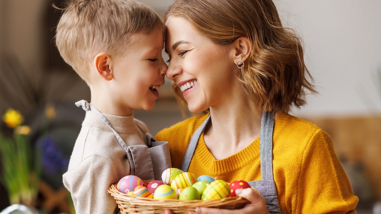 mother and son in the kitchen smiling holding a basket of eggs