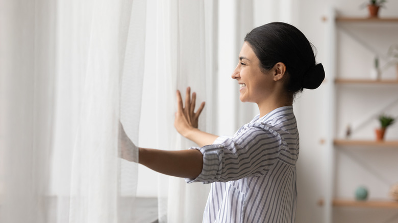 woman opening curtains