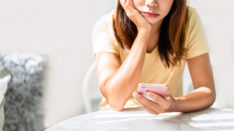 Sad girl looking at phone