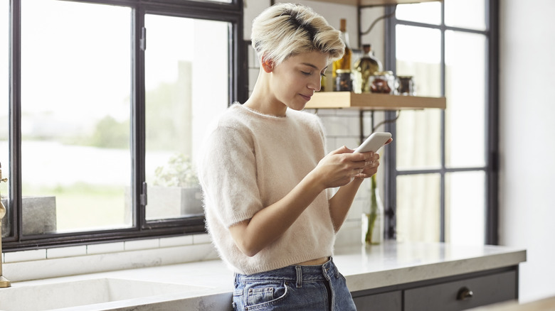 Person in kitchen holding phone