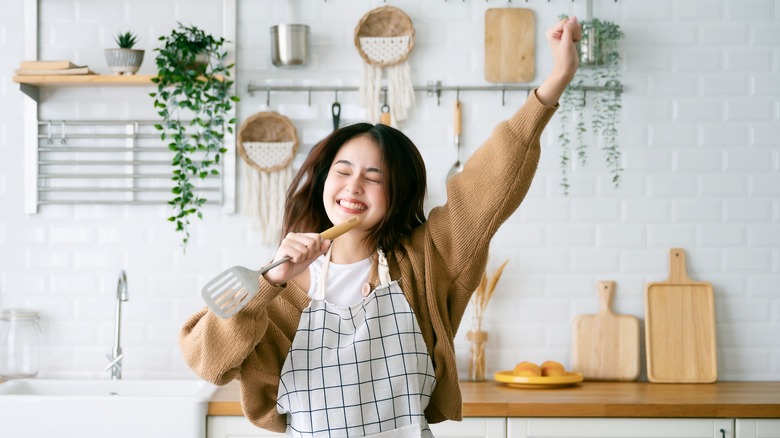 Woman dancing in kitchen with spatula 