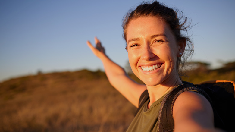 A woman taking a selfie outdoors with her hair blowing