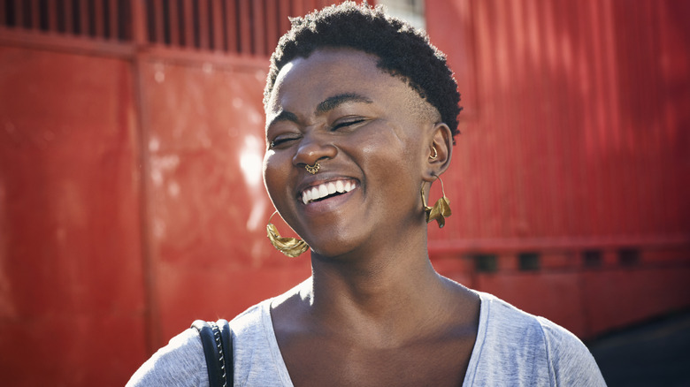 A woman wth short hair and a nose piercing smiling