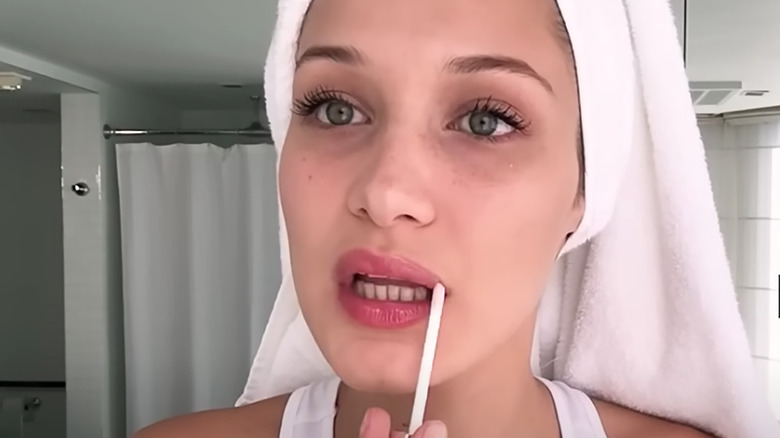 Bella Hadid applying lip gloss