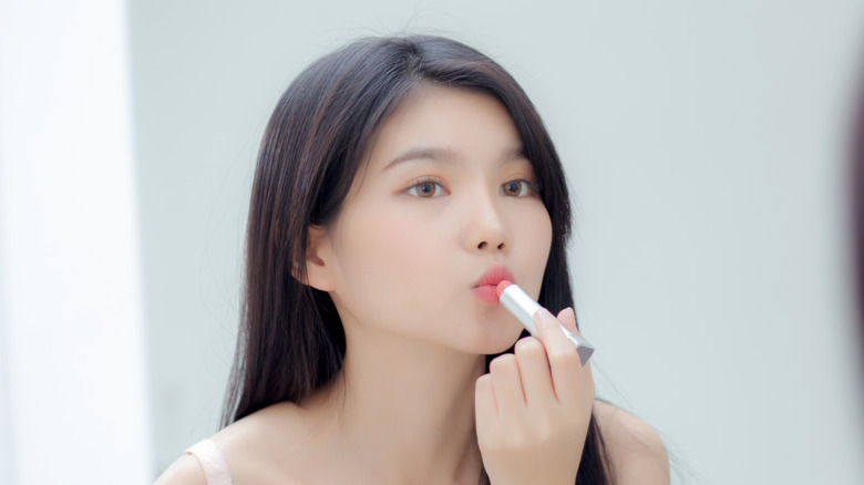 Woman applying pink lipstick