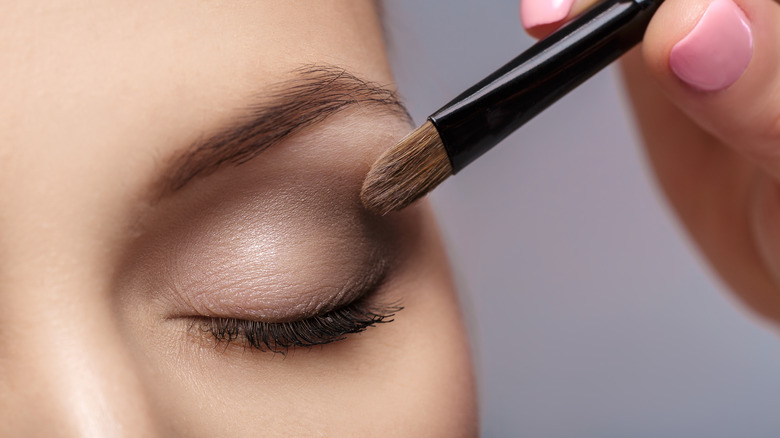 Hand applying eyeshadow to model's eyelid