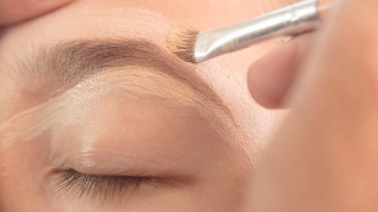 Applying concealer over eyebrow