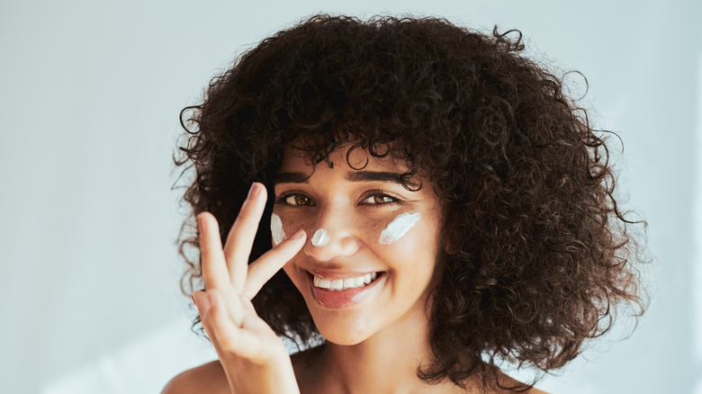 woman applying lotion to nose