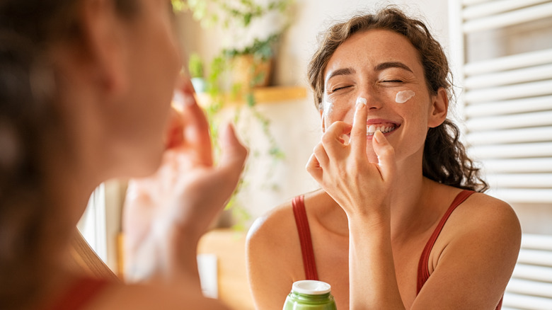 smiling woman applying retinoid product