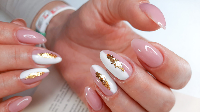 close up of a pink and white manicure with gold design