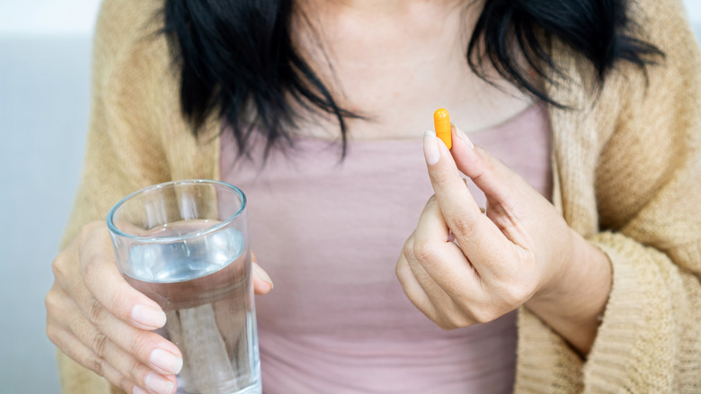 Woman holding a vitamin and a glass of water