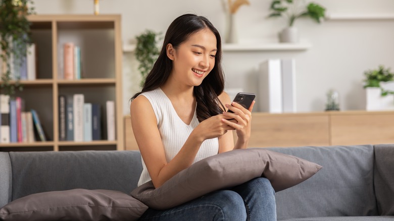 young woman on couch looking at phone