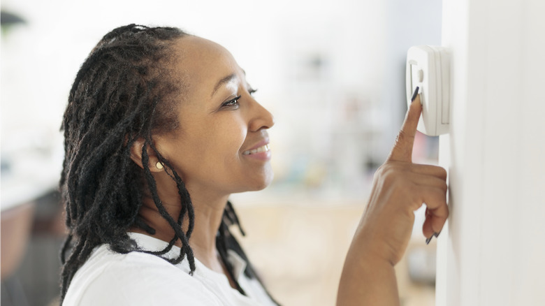 Woman turning down the thermostat 