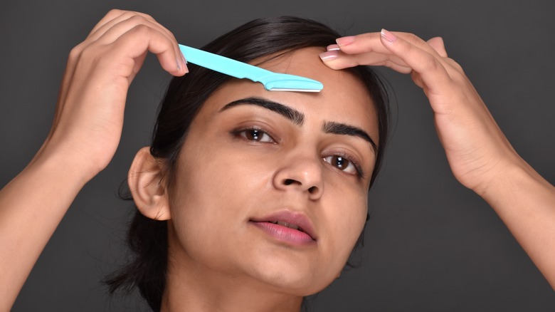 woman shaving eyebrows