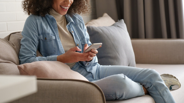 woman texting on couch 