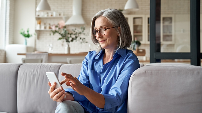 older woman texting on couch 