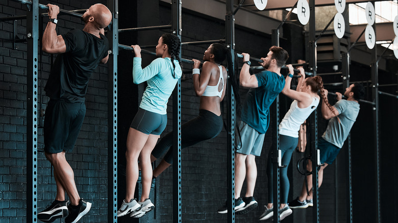 Group of people hanging on pull-up bar