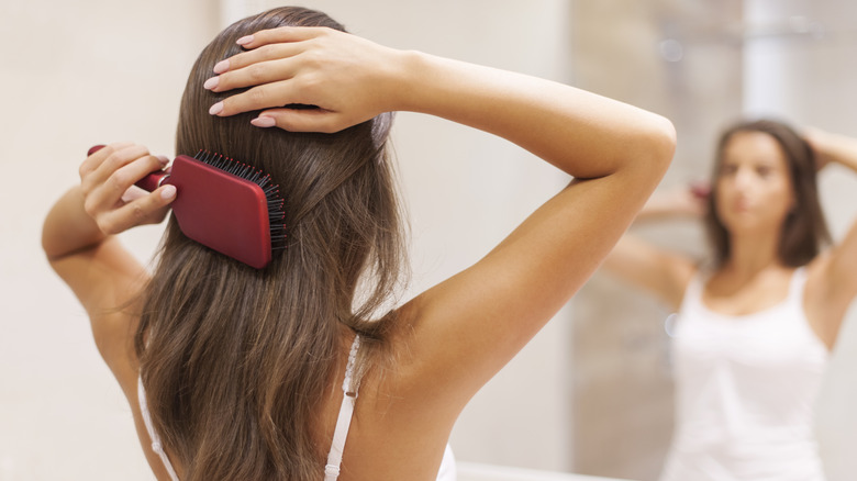 woman brushing hair in mirror